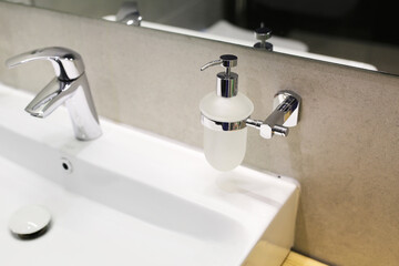 Liquid soap on the washbasin. Hygiene concept. Liquid soap tube.Liquid cute in a glass flask with a dispenser. Hand hygiene soap in the bathroom.