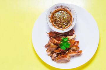Grilled pork mask was marinated with minced coriander root, black pepper and garlic and served with Thai spicy sauce (Jaew sauce).