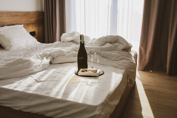 Bedroom with a spread bed. White linens on the bed with champagne and glasses. Summer.
The sun's...