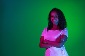 Latino young woman's portrait on dark studio background in neon. Concept of human emotions, facial...