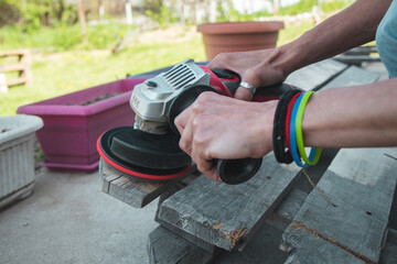 Female hands process wooden boards, pallet with a sanding machine
