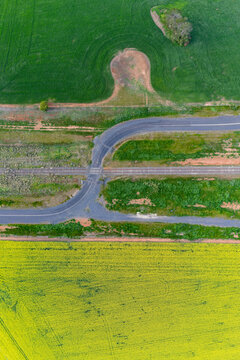 Aerial view of a country road winding through a railway crossing along side farmland
