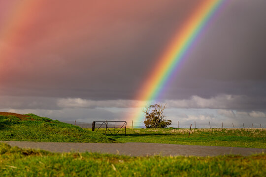A vivid rainbow arching over a dam on farmland