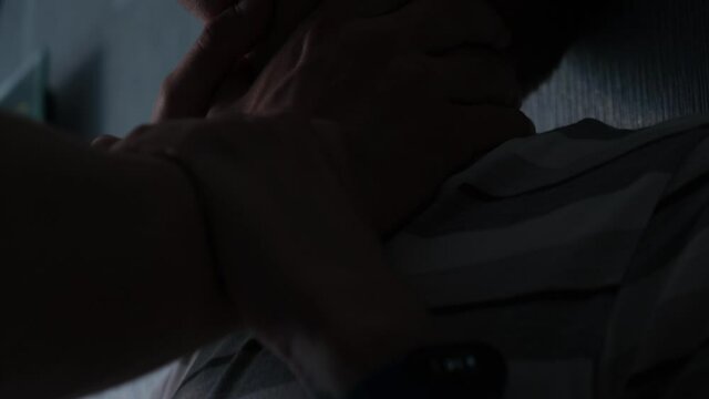 The perpetrator chokes the victim in a dark room