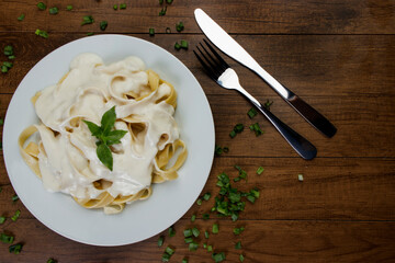 Tagliatelle pasta served with bechamel sauce and basil leaves. Pasta with white sauce. Top view photo with space for text.