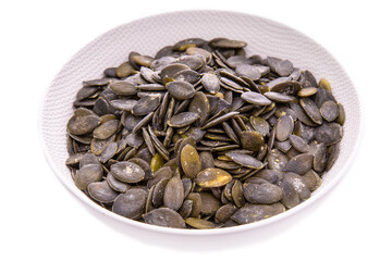 peeled pumpkin seeds in a white plate on a white background. Isolated items and products