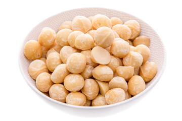 macadamia nut kernels in a white plate on a white background. Isolated items and products