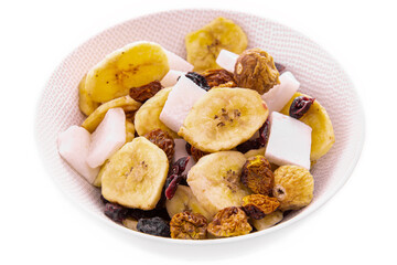 a mixture of chopped dried fruits and berries, nuts in a white plate on a white background. Isolated items and products