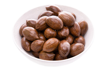 Pecans in a white plate on a white background. Isolated items and products