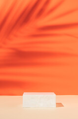 Minimal modern product display on orange background with podium with tropical palm leaf shadow....