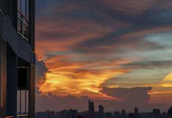 Beautiful sunset sky above clouds with skyscraper evening time with residence balcony and dramatic...