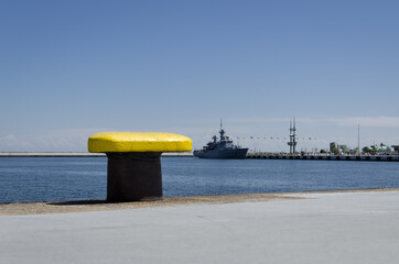 YELLOW BITT - Seaport wharf with warship in the background 