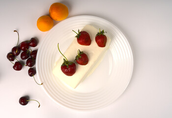 White ice cream is on a white plate with juicy strawberries.