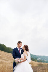 A young couple hugs in a field next to the river on their wedding day. Happy couple. Wedding photo. Couple in love