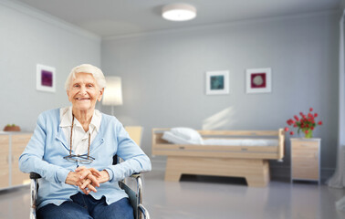 Seniorin im Rollstuhl vor Bett im Pflegeheim