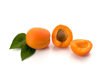 Whole apricot with leaves and one cut in half with the seed, isolated on white