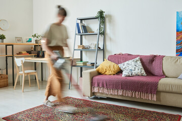 Blurred motion of housewife doing housework in the room at home