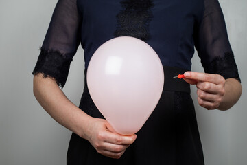 Orange balloon and needle in a woman's hand. Bloated stomach