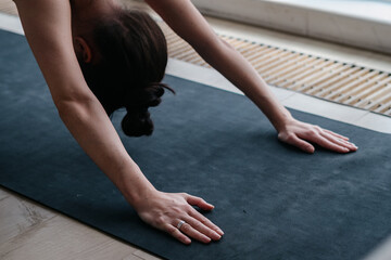 Fototapeta na wymiar Cropped view of woman performing downward facing dog yoga position