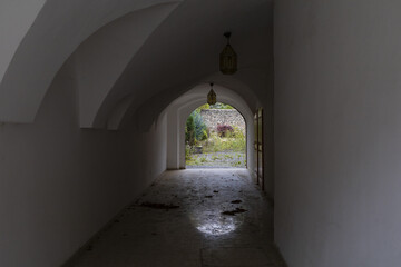 Dark tunnel arch in medieval house with open gate in the end