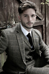 Handsome English gangster dressed in waistcoat and jacket sitting and looking at camera
