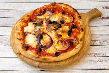 Typical Italian pizza with red onion, black olives, canned tuna, mozzarella cheese and pomodoro