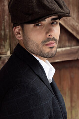 Handsome latino gangster dressed in waistcoat and jacket sitting and looking at camera