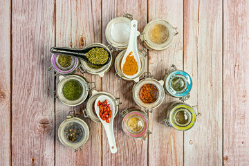 Fototapeta na wymiar Hermetic jars of assorted spices decorated with porcelain spoons with curry, spices and cayenne