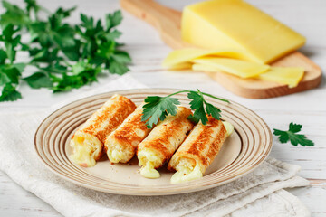 Fried rolls of bread and parmesan cheese with parsley on a plate on a white wooden background. Breakfast. Brunch. A delicious snack for gourmets. Selective Focus
