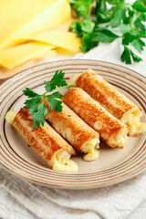 Fried rolls of bread and parmesan cheese with parsley on a plate on a white wooden background. Breakfast. Brunch. A delicious snack for gourmets. Selective Focus