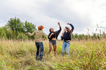 Fototapeta na wymiar Summer holidays vacation happy people concept. Group of three friends boy and two girls dancing and having fun together outdoors. Picnic with friends on road trip in nature.