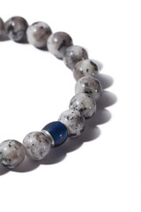 Cropped shot of beaded bracelet made of gray marble and decorated with blue cat eye bead. Stylish bracelet is isolated on the white background. 