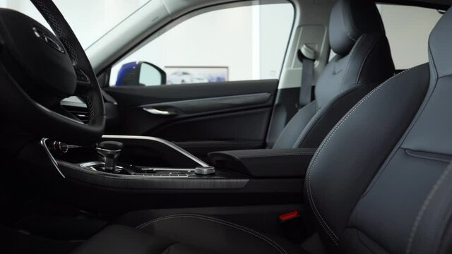 Close-up of the front car seats made of gray leather with white stitching.