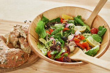Close-up of bowl with vegetable salad and fresh bread on the table