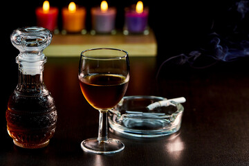 glass of alcohol and bottle with cigarette isolate on black 
