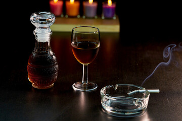 glass of alcohol and bottle with cigarette isolate on black 