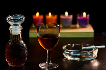 glass of alcohol and bottle with cigarette isolate on black 