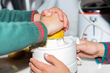 child hands make lemon juice in kitchen with school green uniform, white juice machine and white cook background