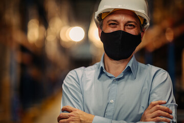 Manager with face mask in warehouse looking confident