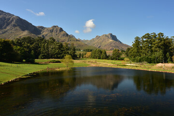 A huge pond against a scenic mountain and blue sky backdrop in the Western Cape in South Africa