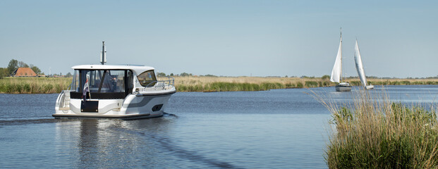 Yacht. Motor boat. Pleasure boat. Pleasure cruising. Frisian canals. Friesland. Luxury ship. Water cruising. Leisure. Summer. Netherlands. On deck.Sailing boats.Panorama.