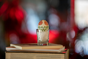 Easter egg in a glass with salt on stack of books