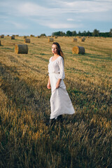 beautiful woman in a white dress walks across the field.