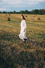Naklejka na ściany i meble beautiful woman in a white dress walks across the field.