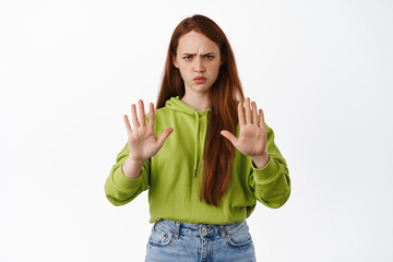 Stop right there. Angry and serious redhead woman stretch hand to block, refuse action, prohibit...