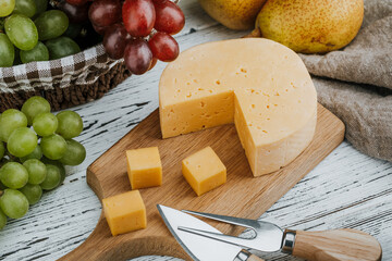 Cheese dish with organic cheeses, fruits, nuts on a wooden background. Delicious cheese snack