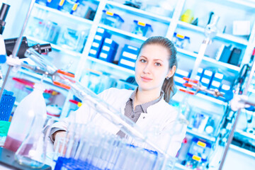 Young female student at university chemistry laboratory smiling and posing at camera