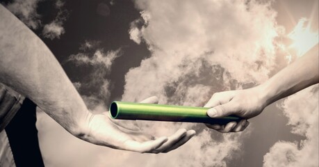 Mid section of hand passing a baton against clouds in the sky