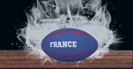 Blue rugby ball with france text over wooden surface against smoke effect on black background