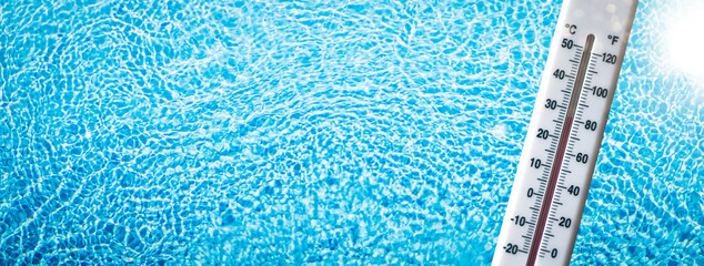 Symbolbild Hintergrund Wassertemperatur - Blaues Poolwasser mit Sonnenreflektionen hinter einem Thermometer, welches warme Temperaturen anzeigt- Hotelpool, Urlaubsfeeling - obrazy, fototapety, plakaty